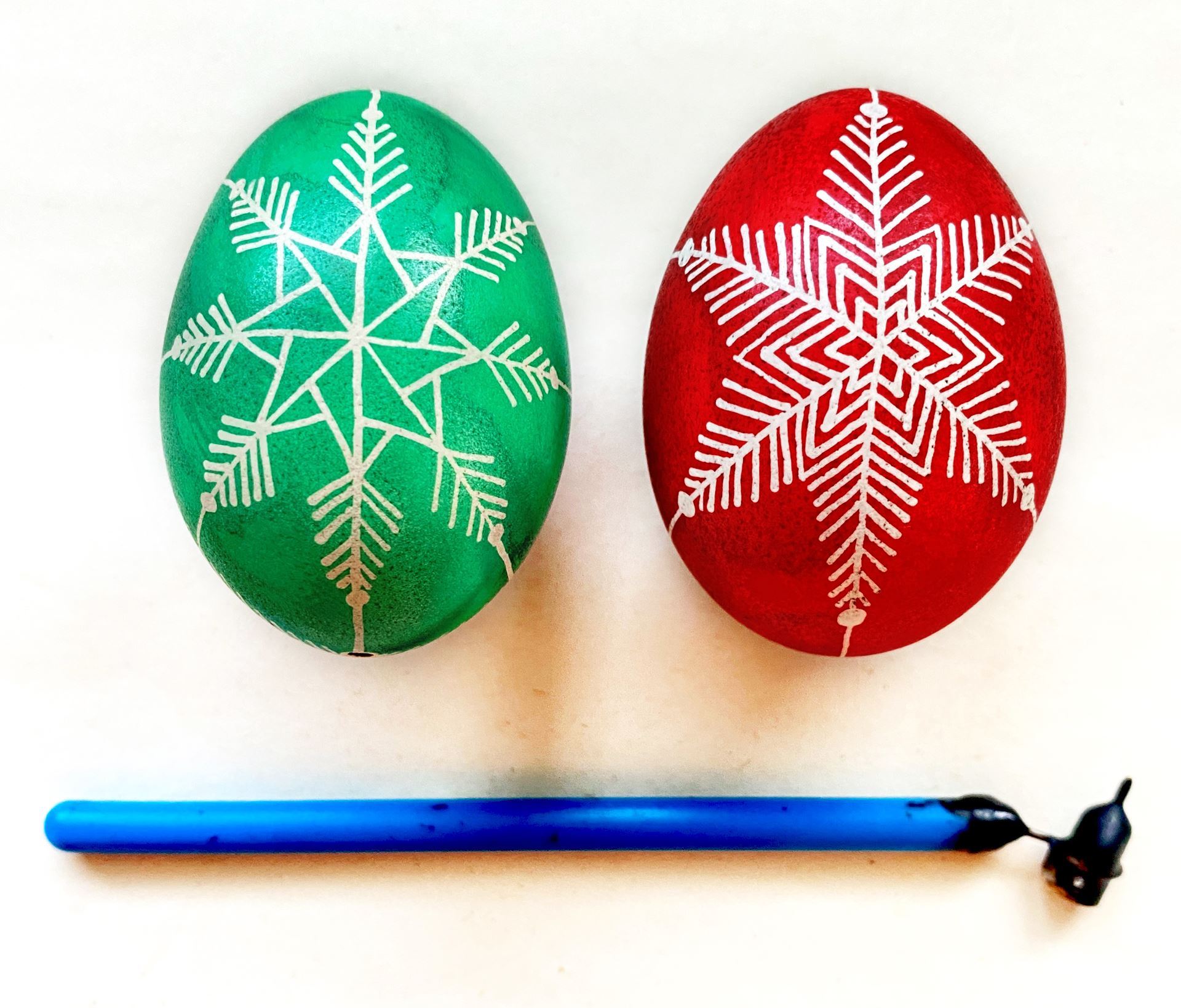 Using wax resist, the Pysanky is a unique egg-decorating technique reveals designs on colorful eggs. Pictured a "kistka" hot wax pen, and a green and red Pysanky decorated eggs.
